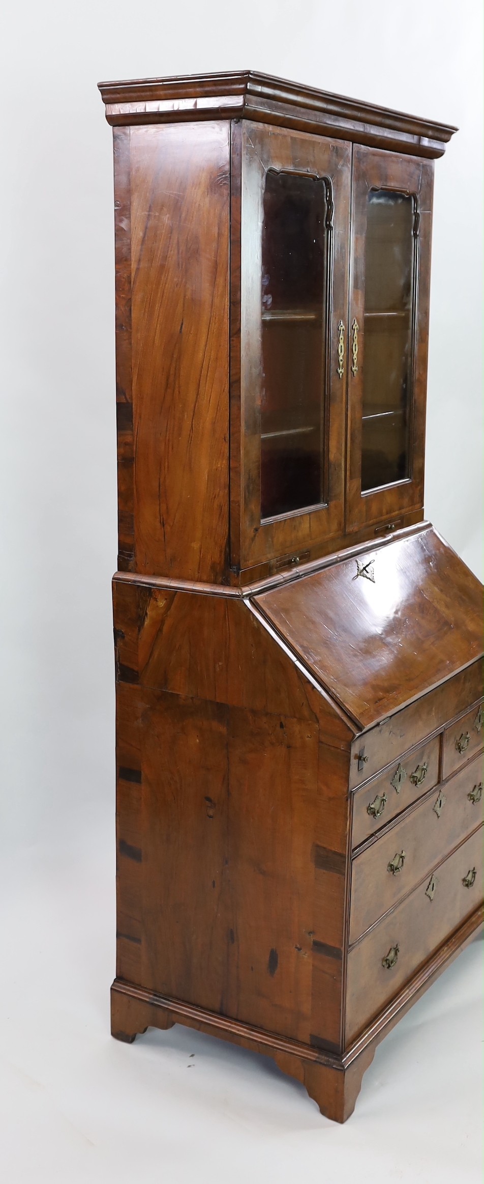 An early 18th century feather banded walnut bureau bookcase, width 96cm depth 57cm height 198cm